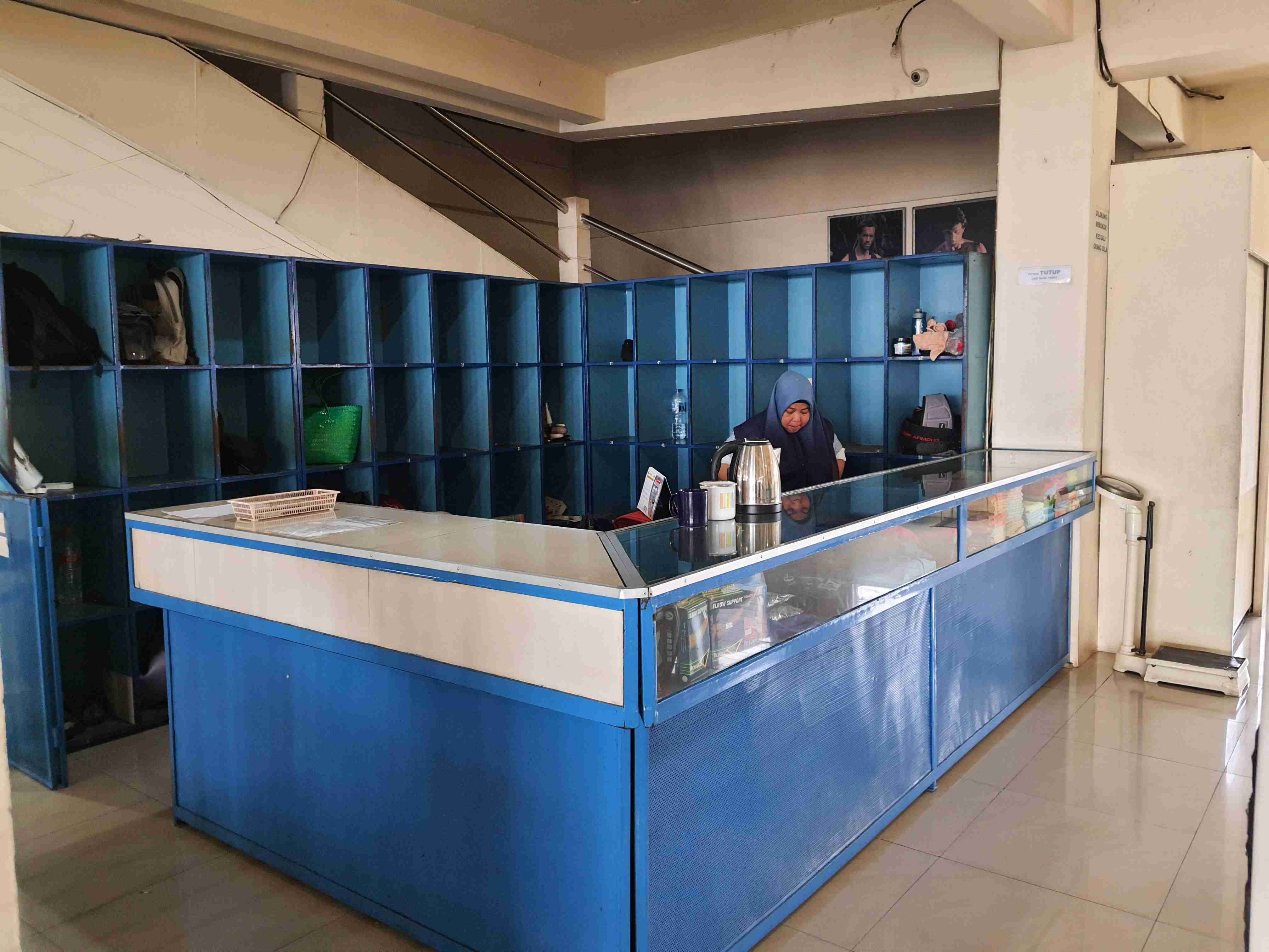 Foto meja resepsionis berwarna biru dengan loker-loker di belakangnya.